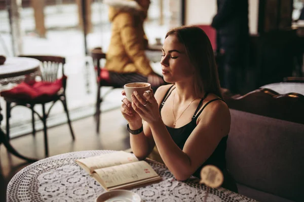 Молодая женщина пьет кофе в кафе — стоковое фото