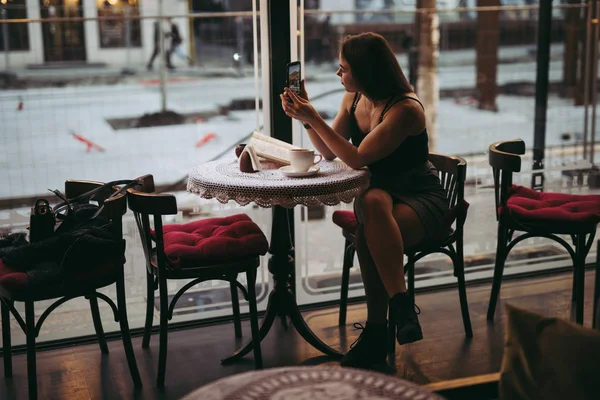 Kafede akıllı telefonla oynayan kadın — Stok fotoğraf