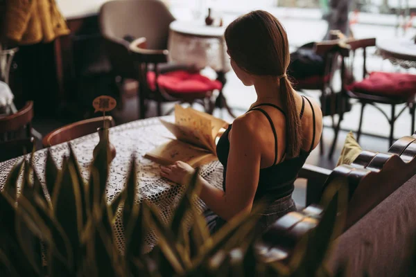 Ung kvinne leser bok på kafe – stockfoto