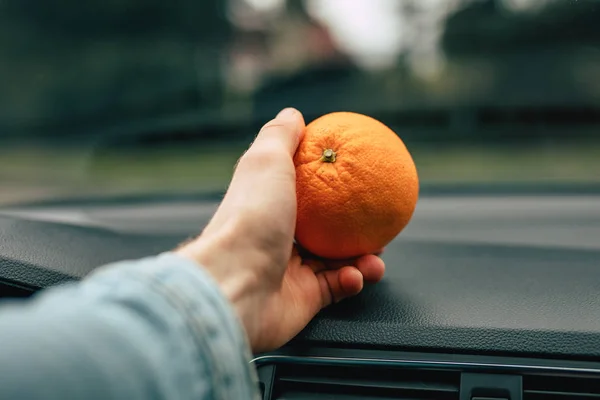 Light orange snack in the car, hand take ripe fruit