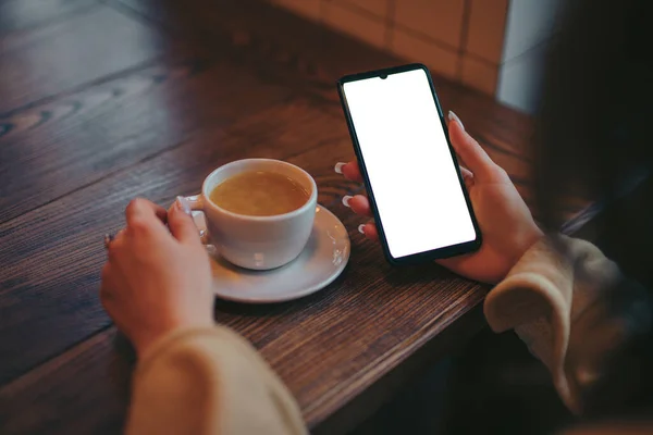 Mockup of woman holding smartphone in cafe near tea cup — ストック写真