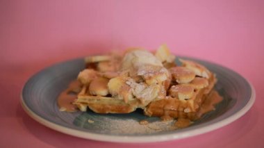 Sprinkling sugar powder on sweet banana waffle