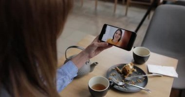Woman video chatting with her friend holding smartphone