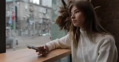 Young woman listening her favorite music with earphones in cafe