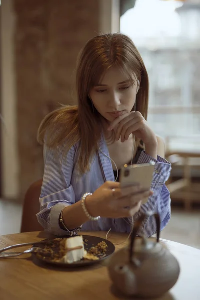 Ung kvinne som lytter til musikk med øretelefoner på kafe – stockfoto