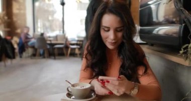 Kafede akıllı telefon kullanan bir kadın.