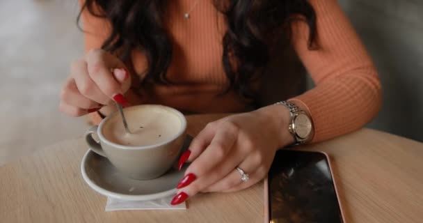 Primer plano de una mujer irreconocible mezclando azúcar en su taza de café con leche — Vídeos de Stock