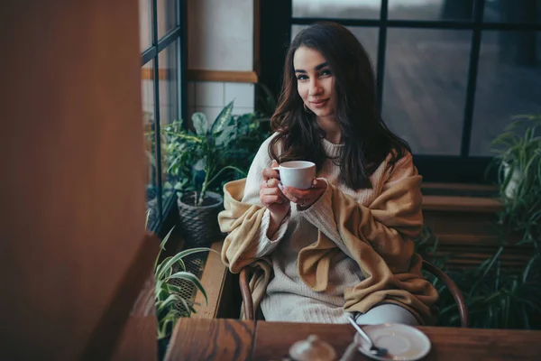 Nuori nainen juo teetä kahvilassa — kuvapankkivalokuva