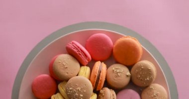 Female hand take one macaroon from rotating colorful cakes set