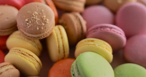 Female hand put one macaroon into rotating colorful cakes set — Stock Video