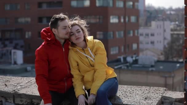 Happy couple sitting on roof, man embracing woman — 图库视频影像