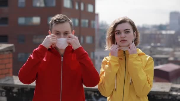 Епідемія вірусу, жінка і чоловік в масці для обличчя на даху міста — стокове відео
