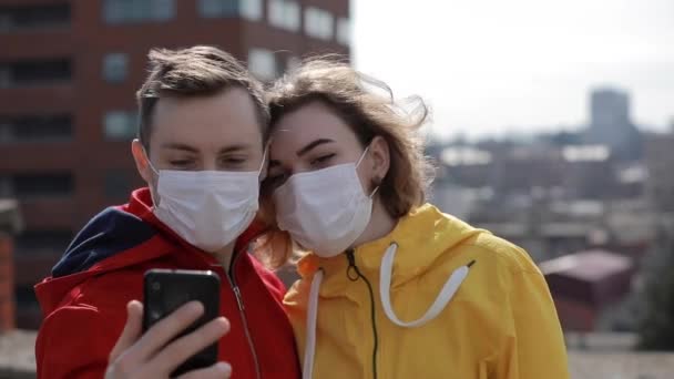 Couple make selfie in surgical masks on the city roof — Stock video