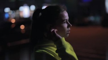 Kendine güvenen sporcu kadın geceleri kablosuz kulaklık takıyor.