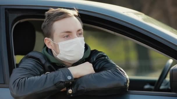 Homem de máscara cirúrgica olhando através da janela em um carro — Vídeo de Stock