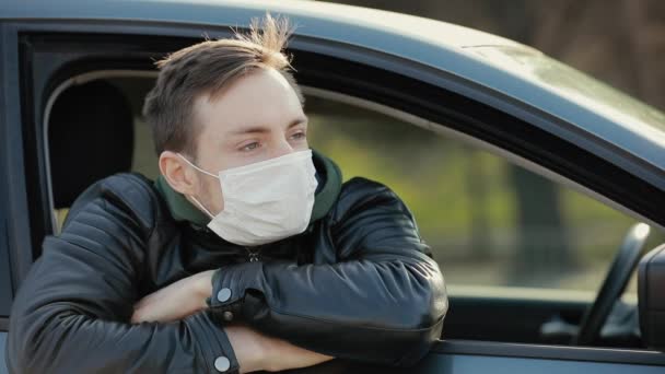 Ευτυχισμένος άνθρωπος με χειρουργική μάσκα κοιτάζοντας μέσα από το παράθυρο σε ένα αυτοκίνητο δείχνει τους αντίχειρες επάνω — Αρχείο Βίντεο