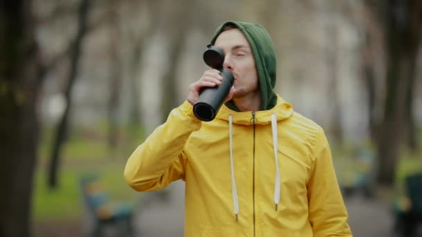 Hombre deportivo bebiendo té de la botella en el parque — Vídeos de Stock