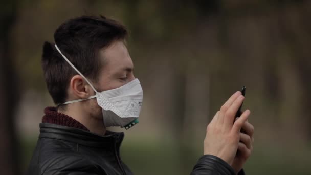 Hombre usando smartphone con máscara quirúrgica en un parque — Vídeo de stock