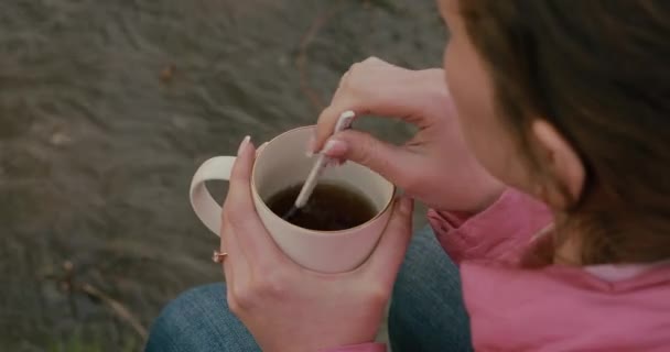 Woman drinking tea near river. Original audio included. — Stock Video