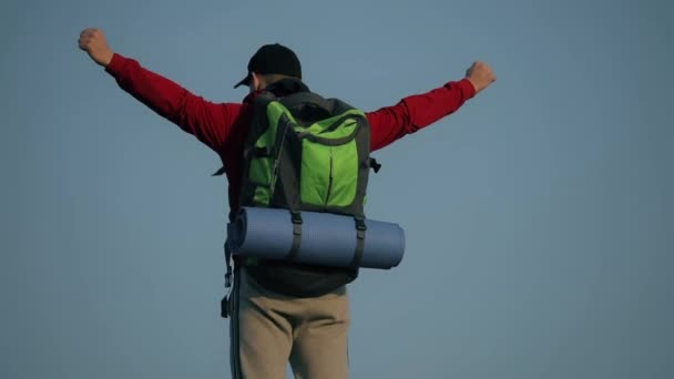 Hombre de turismo disfrutando de la libertad con las manos levantadas sobre fondo azul cielo — Vídeo de stock