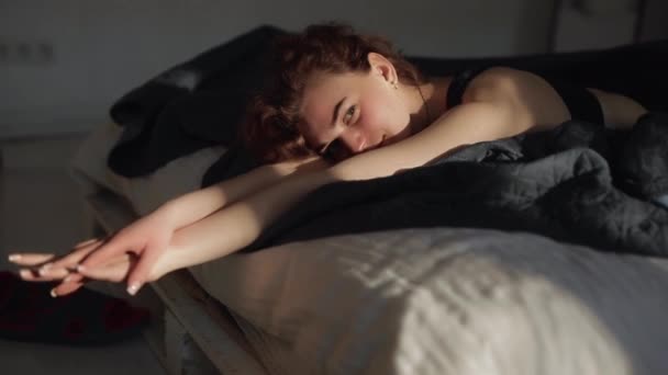 Tôt le matin, mignonne femme se réveille dans un lit — Video