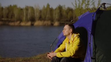 Kamp yapan adam kamp çadırında oturuyor.