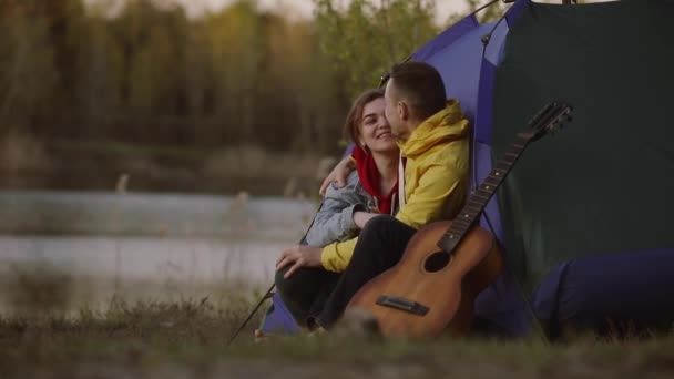 Пара расслабляющих поцелуев вместе сидя в палатке лагеря — стоковое видео