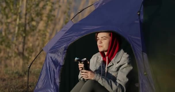 Camping femeie care stă în cort bea ceai de la termos — Videoclip de stoc