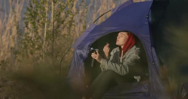 Camping-Frau sitzt im Zelt und isst Snack — Stockvideo