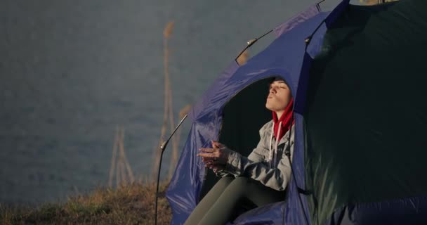 Женщина из кемпинга сидит в палатке и ест шоколад — стоковое видео