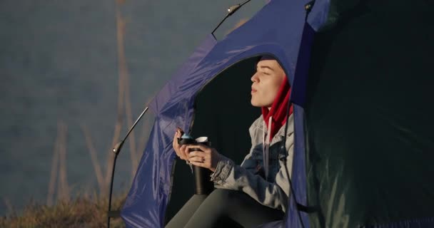 Kamp yapan kadın çadırda oturmuş çikolatayla çay içiyor. — Stok video