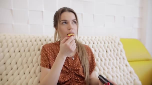 Vrouw die chips eet zit thuis — Stockvideo