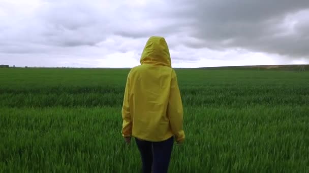 Mujer con chaqueta amarilla mira en las nubes en el día nublado — Vídeo de stock