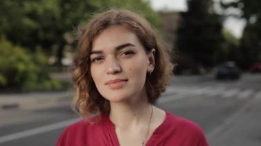 Kendine güveni tam güzel bir kadının portresi. Şehir caddesinde kameraya bakıyor.