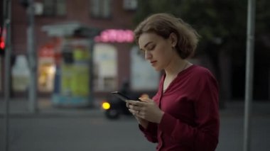 Şehir caddesinde yürürken akıllı telefonla mesajlaşan bir kadın.