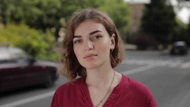 Portret van een mooie zelfverzekerde vrouw die in een straat naar de camera staart — Stockvideo