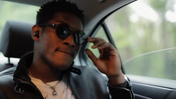 Cool hombre afroamericano escuchar música sentado en un coche — Vídeos de Stock