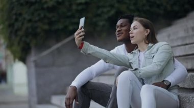 İki çok ırklı arkadaş akıllı telefondan selfie çekiyor.