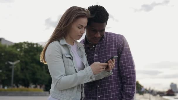 Deux amis multiraciaux regardant vers le bas dans le smartphone — Video