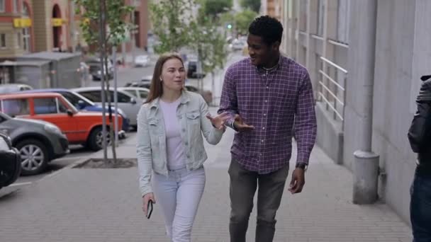 İki çok ırklı arkadaş şehirde yürüyor ve konuşuyor. — Stok video