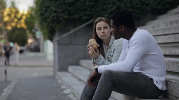 Biała kobieta karmi swojego afrykańskiego przyjaciela w mieście — Wideo stockowe
