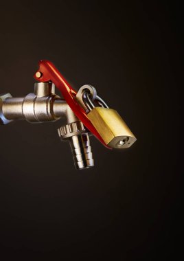 Arka planda asma kilit olan bahçe musluğu