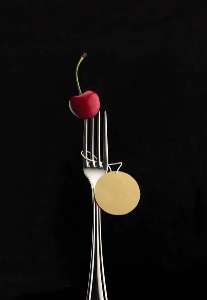 red cherry on fork on a black background