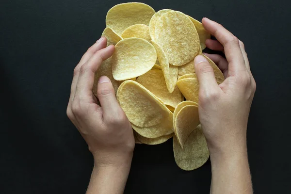 Куча картофельных чипсов и женские руки. Фотография фастфуда — стоковое фото
