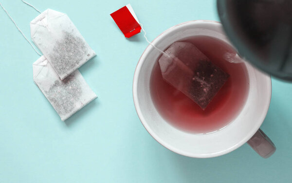 Ceramic cup with red fruit tea and paper tea bags. Hot water is 