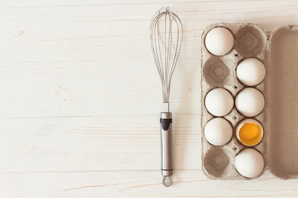 Metal çırpma teli ve karton çiğ beyaz tavuk yumurtası ve beyaz w — Stok fotoğraf