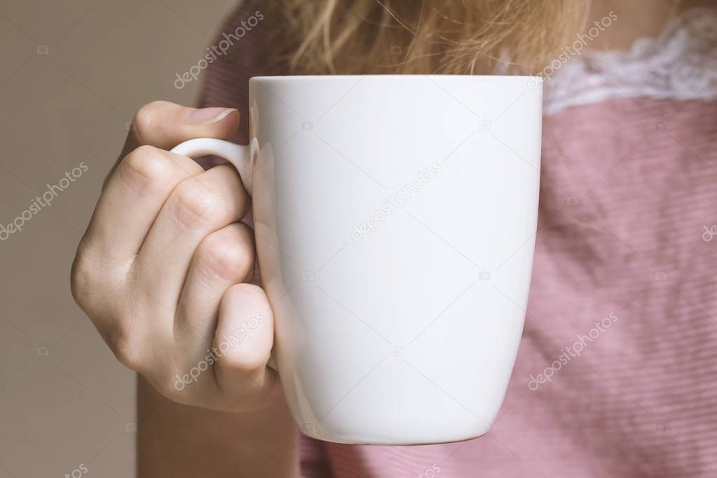 Young woman holding white cup. 