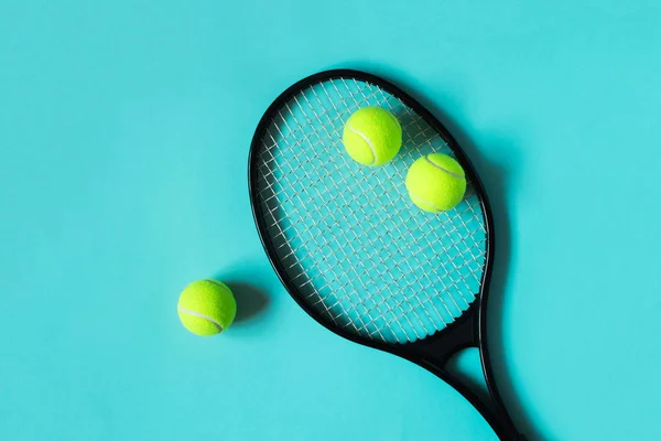 Tennis balls and racket on blue background. Sport equipment. Flat lay.