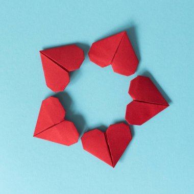Mavi bir arka plan üzerinde kırmızı kalpler origami çerçevesinden. Sevgililer günü kavramı. Yukarıdan görüntülemek.