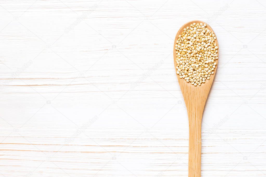 Wooden spoon with White Quinoa seeds on white wooden table. Concept of a healthy diet. Super food.